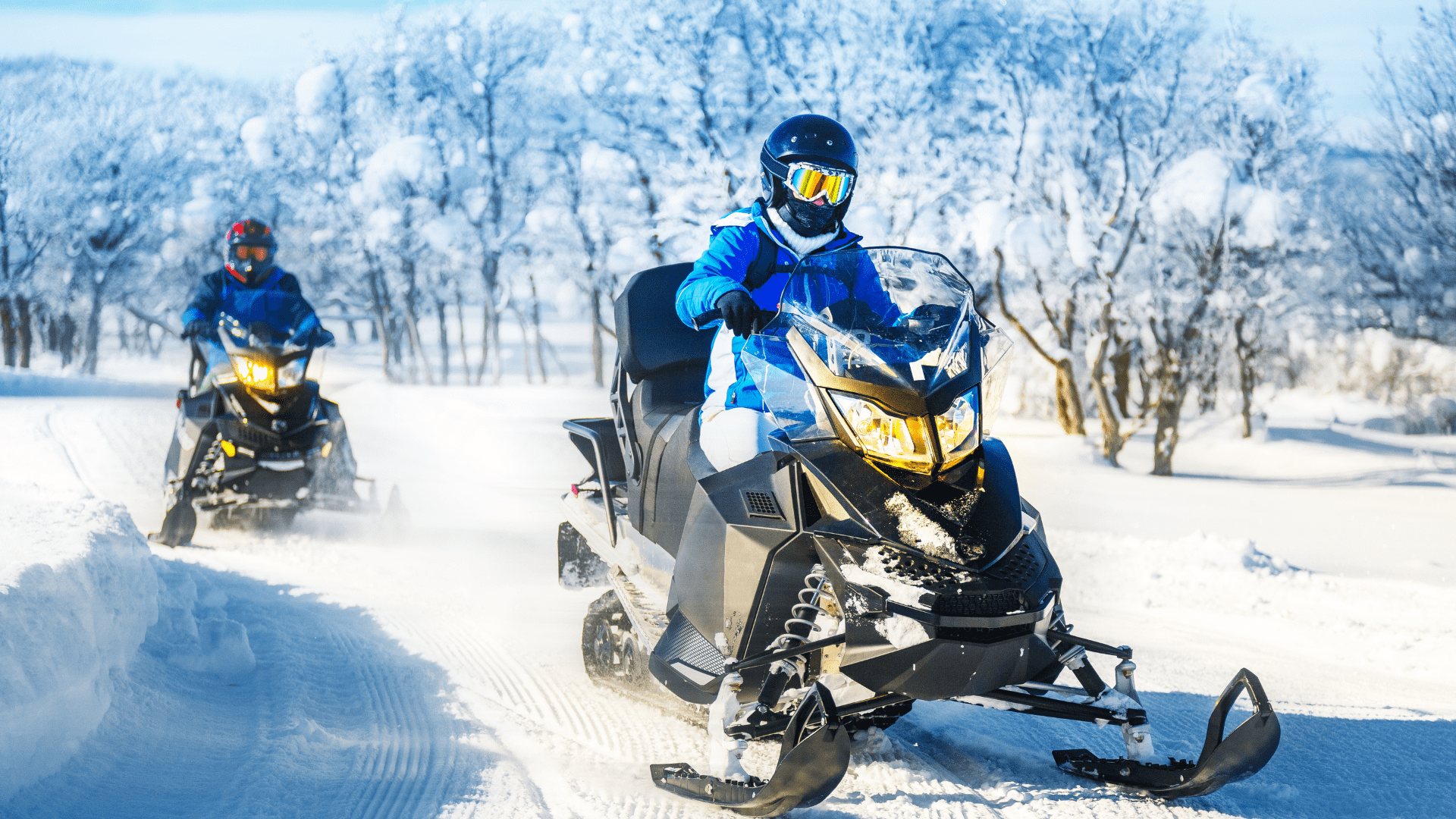 Bild: Två personer klädd i blått åker på varsin snöskoter. Syfte: Det går att stöldspåra en snöskoter