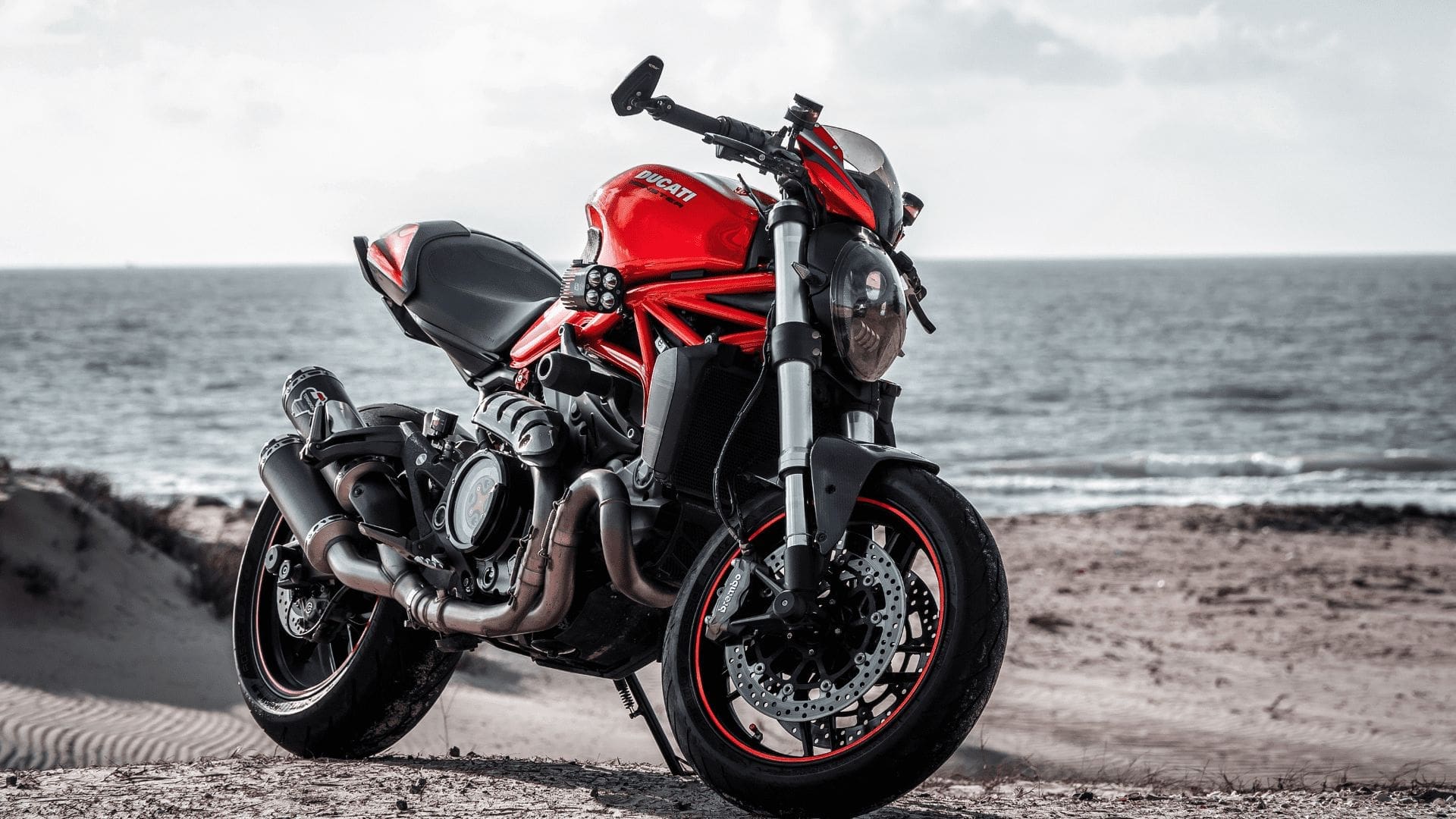 En rödsvart ducati motorcykel som står nära havet