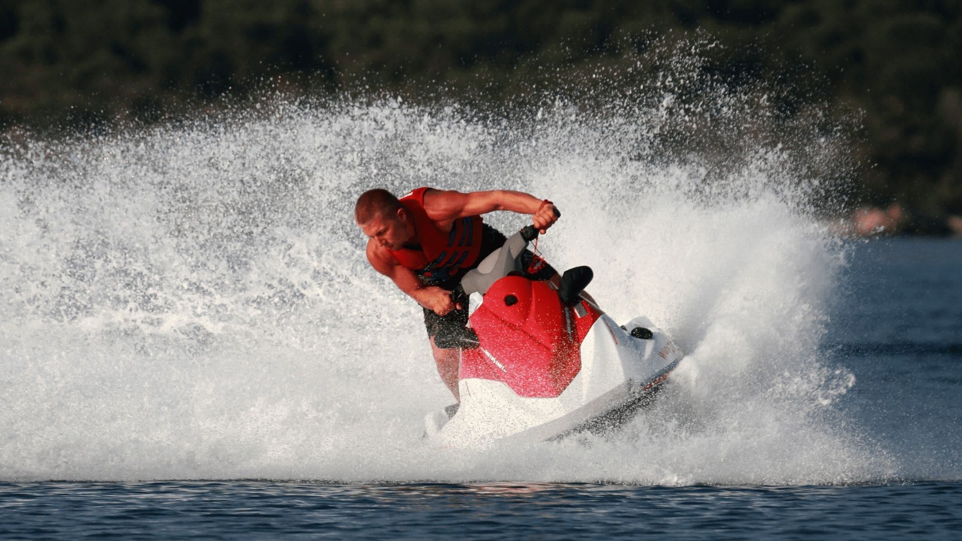 En vältränad man som åker på en rödvit vattenskoter