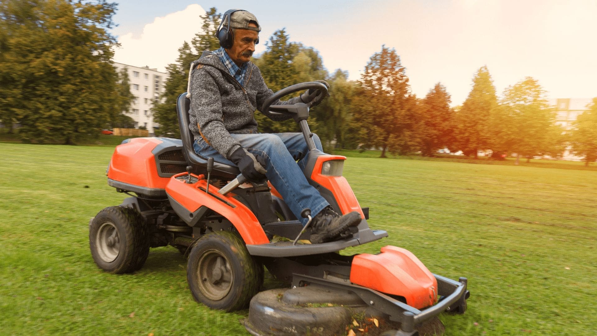 En man på en orange åkgräsklippare